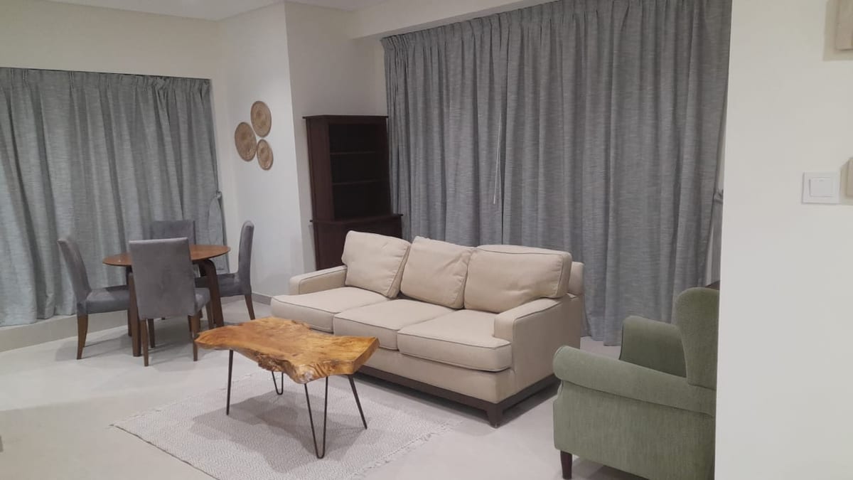 Apartment living and dining area with a beige sofa, a round table and grey curtains